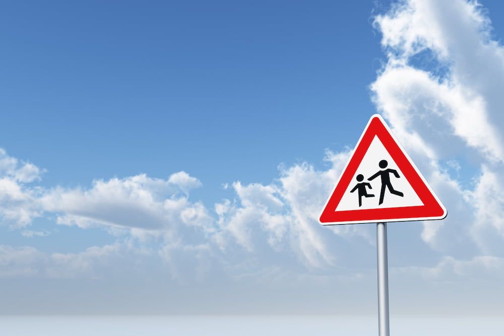 Straßenschild Achtung Kinder, im Hintergrund blauer Himmel mit Wolken